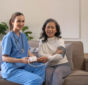 smiling caregiver doing BP to elder