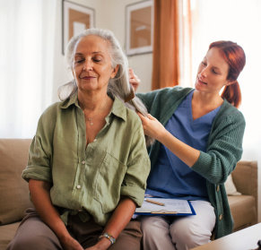 caregiver combing the hair of senior woman