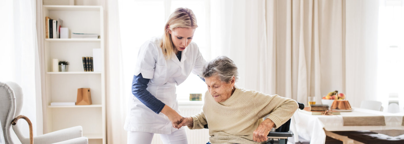 nurse assisting elder to stand from wheelchair