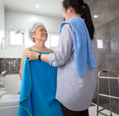 nurse assisting elder in taking a bath